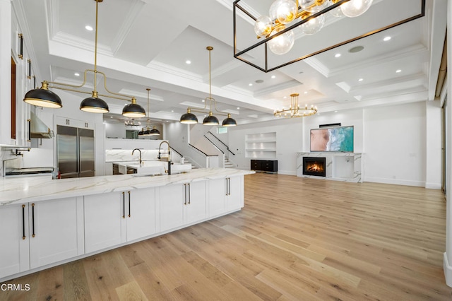 kitchen with built in refrigerator, light hardwood / wood-style flooring, pendant lighting, and white cabinetry