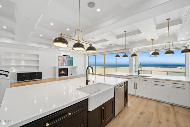 kitchen with light wood-type flooring, sink, white cabinets, coffered ceiling, and decorative light fixtures