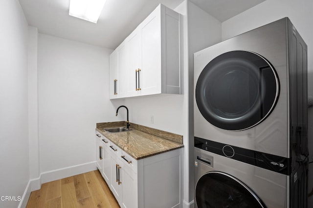 washroom featuring cabinets, light hardwood / wood-style flooring, sink, and stacked washing maching and dryer