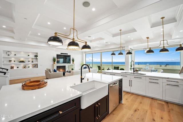 kitchen featuring light hardwood / wood-style flooring, white cabinets, decorative light fixtures, and sink