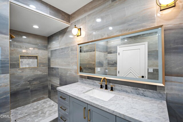 bathroom with tile walls, walk in shower, and vanity