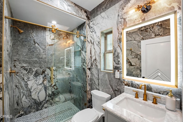 bathroom with tile walls, a shower with door, vanity, and toilet