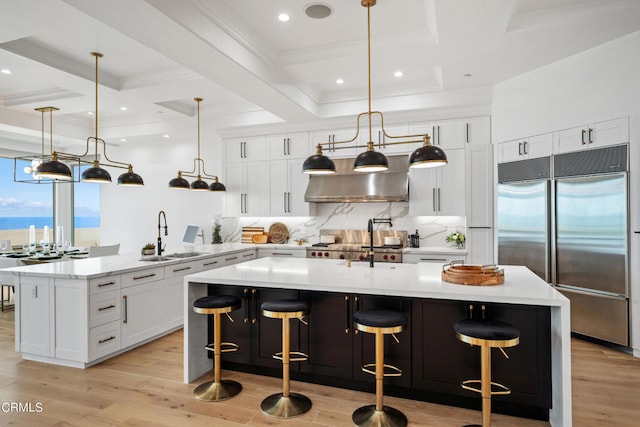 kitchen with pendant lighting, built in refrigerator, a large island with sink, and sink