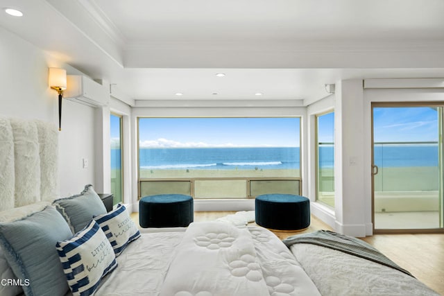 bedroom featuring a water view, ornamental molding, hardwood / wood-style floors, and a wall mounted AC