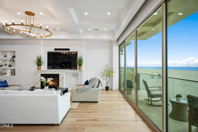 living room with a notable chandelier, light hardwood / wood-style flooring, a fireplace, and crown molding