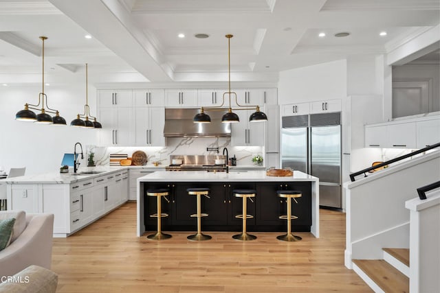 kitchen with white cabinets, beamed ceiling, stainless steel appliances, decorative light fixtures, and sink