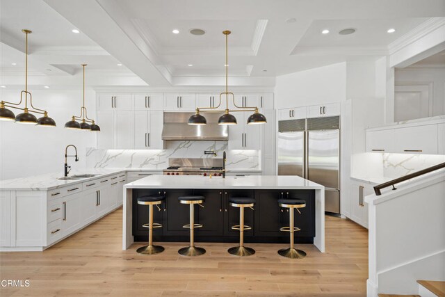 kitchen featuring sink, white cabinets, appliances with stainless steel finishes, decorative light fixtures, and extractor fan