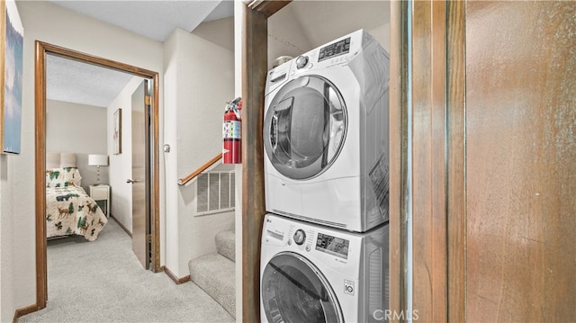 laundry room featuring light carpet, a textured ceiling, and stacked washing maching and dryer