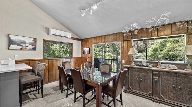 dining space featuring a wall mounted air conditioner, wood walls, track lighting, light colored carpet, and vaulted ceiling