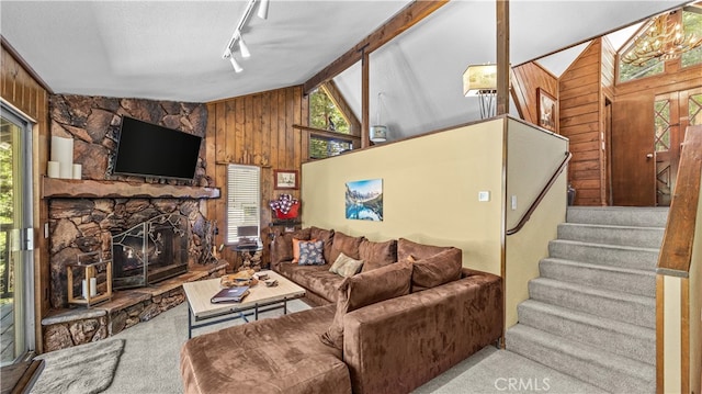 carpeted living room with beamed ceiling, track lighting, a fireplace, high vaulted ceiling, and wooden walls