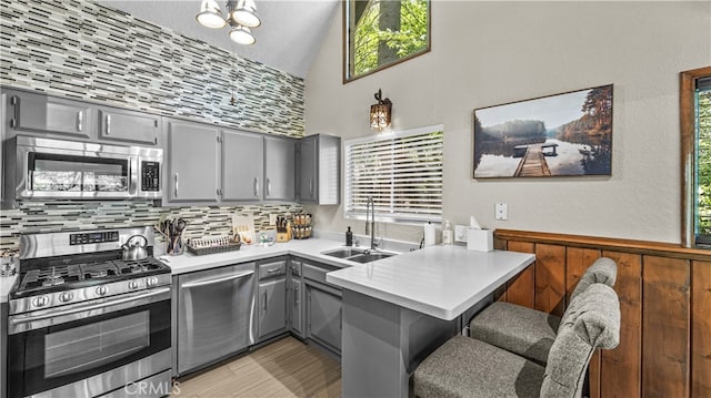 kitchen with sink, stainless steel appliances, kitchen peninsula, and gray cabinetry