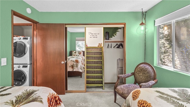 bedroom featuring a textured ceiling, carpet, stacked washer and dryer, and a closet