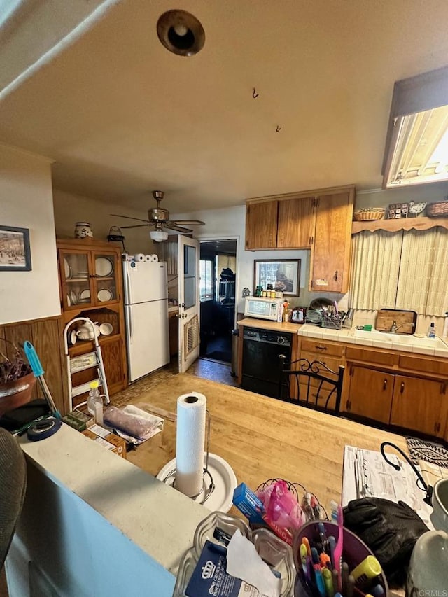 kitchen with tile countertops, ceiling fan, white appliances, and wooden walls