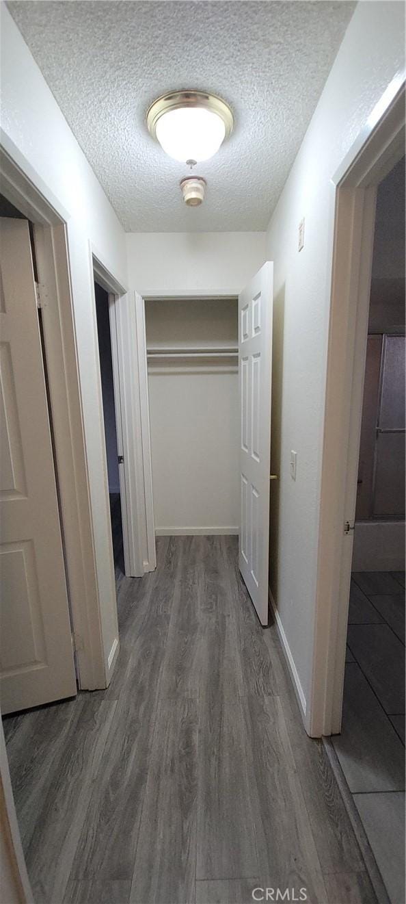 corridor with a textured ceiling and dark wood-type flooring