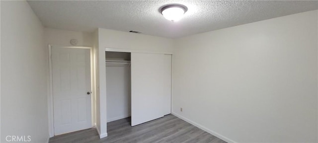 unfurnished bedroom featuring a textured ceiling, hardwood / wood-style flooring, and a closet