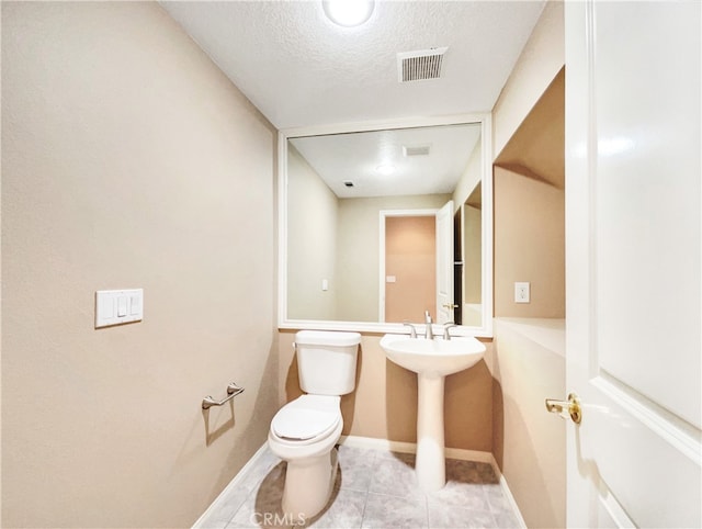 bathroom featuring toilet, a textured ceiling, sink, and tile patterned floors