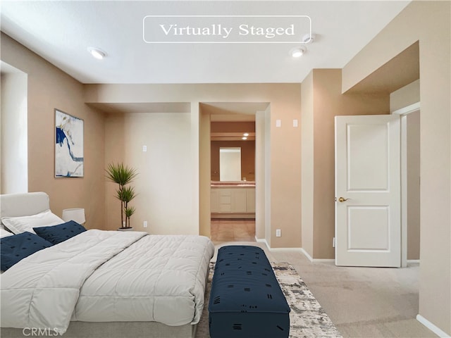 bedroom featuring ensuite bathroom and light colored carpet