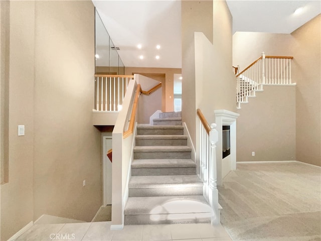 stairway with a towering ceiling and carpet flooring