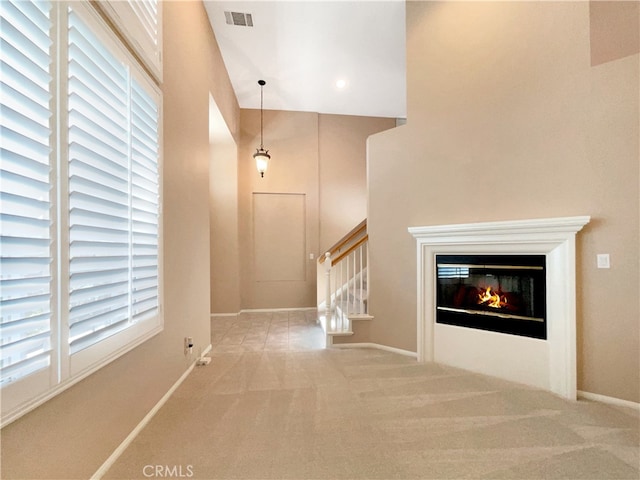 corridor with a healthy amount of sunlight, high vaulted ceiling, and carpet floors