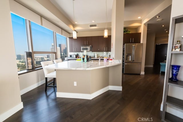 kitchen featuring a kitchen breakfast bar, dark wood-style floors, baseboards, dark brown cabinetry, and appliances with stainless steel finishes