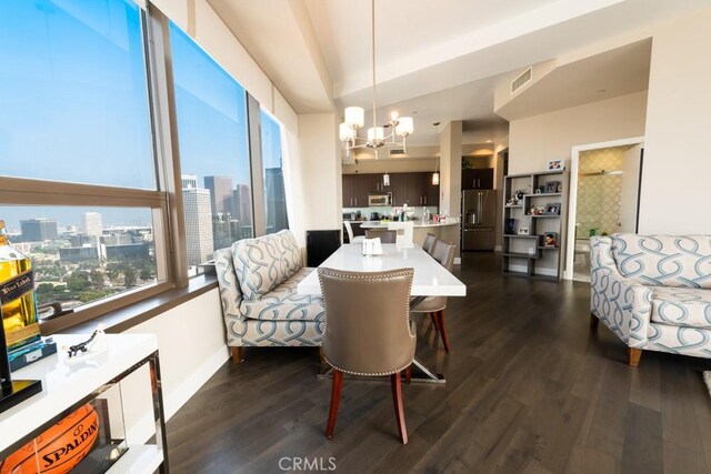 dining area with dark wood finished floors, baseboards, visible vents, an inviting chandelier, and a city view
