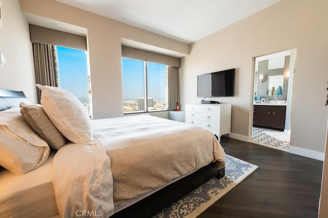 bedroom with a sink, baseboards, ensuite bathroom, and dark wood-style floors