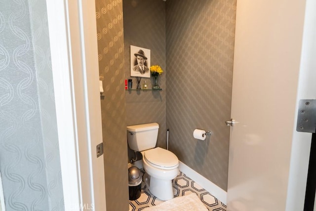 bathroom with wallpapered walls, baseboards, tile patterned flooring, and toilet
