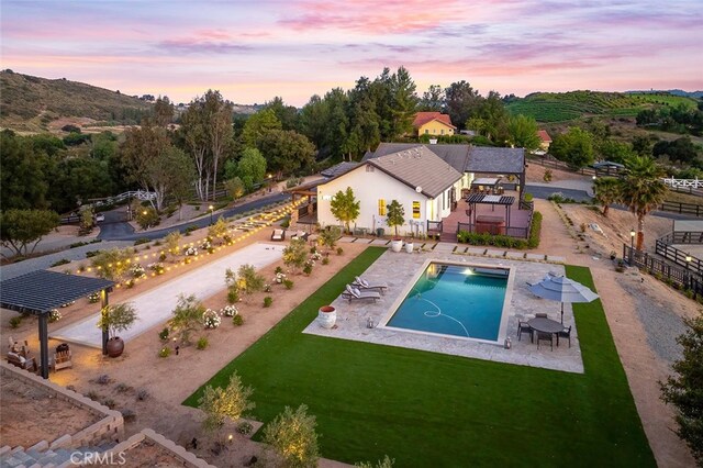 pool at dusk with a yard and a patio