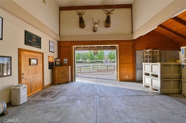 interior space featuring beam ceiling, high vaulted ceiling, wooden walls, and wood ceiling