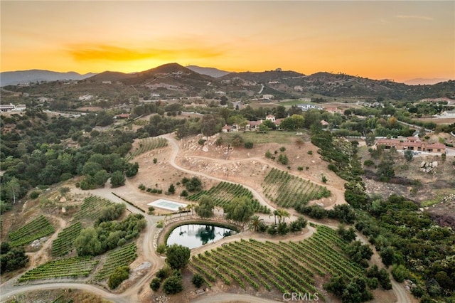 aerial view at dusk featuring a water and mountain view and a rural view