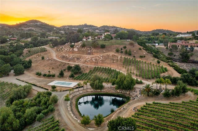 aerial view at dusk featuring a rural view and a water and mountain view