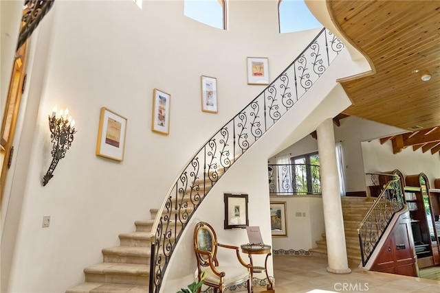 stairway featuring a towering ceiling and wood ceiling