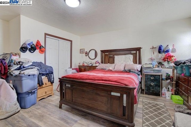 bedroom featuring light hardwood / wood-style flooring, a textured ceiling, and a closet