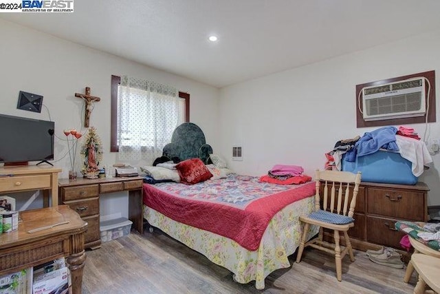 bedroom with a wall mounted air conditioner and hardwood / wood-style floors