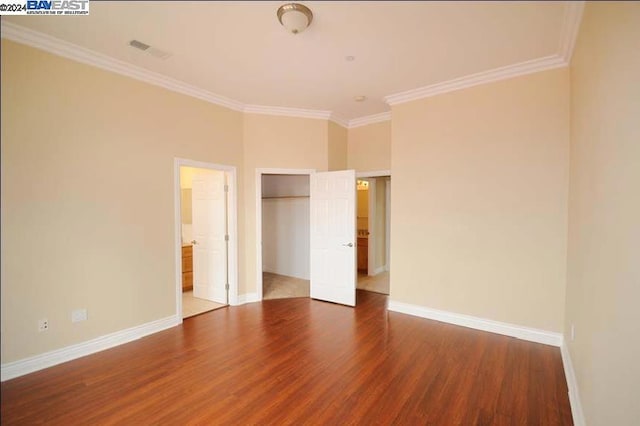 unfurnished bedroom with ensuite bath, ornamental molding, and hardwood / wood-style floors