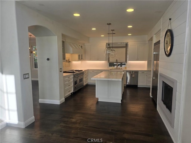 kitchen with premium appliances, light countertops, a kitchen island, and white cabinetry