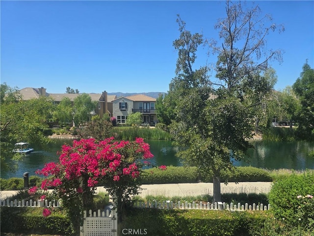 view of home's community with a water view and fence