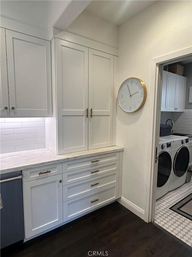 clothes washing area with cabinet space, baseboards, dark wood-type flooring, washer and dryer, and a sink