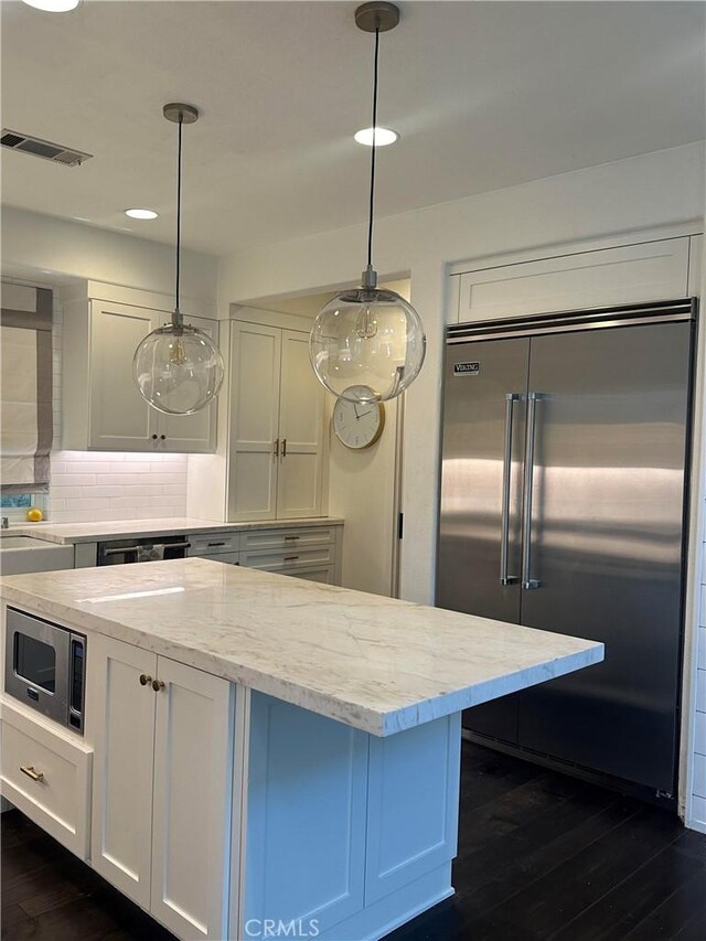 kitchen with pendant lighting, white cabinets, built in appliances, dark hardwood / wood-style floors, and light stone countertops