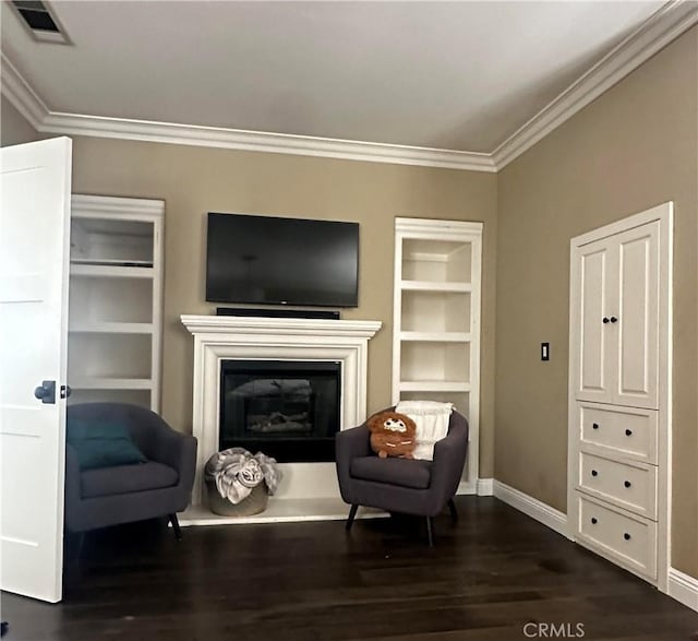 living area featuring built in features, dark wood-style floors, visible vents, ornamental molding, and a glass covered fireplace