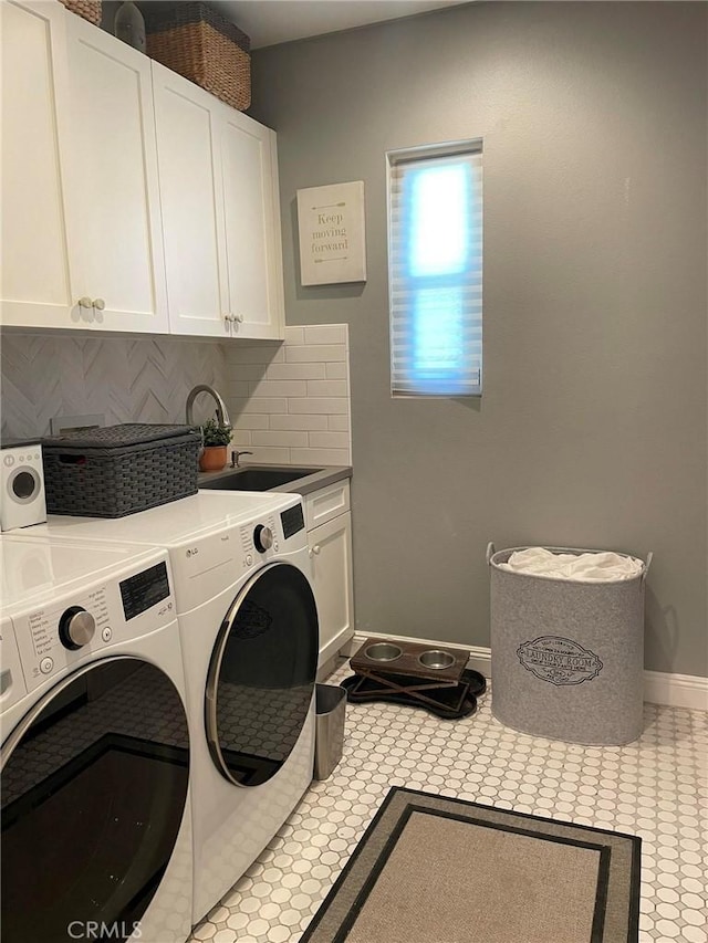 washroom featuring washer and clothes dryer, cabinet space, light tile patterned flooring, a sink, and baseboards