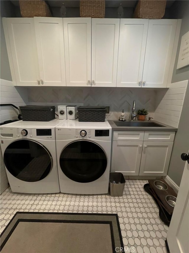 laundry room with cabinet space, a sink, and washing machine and clothes dryer