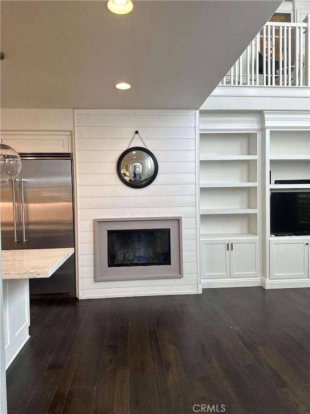 unfurnished living room with recessed lighting, dark wood-style flooring, and a glass covered fireplace