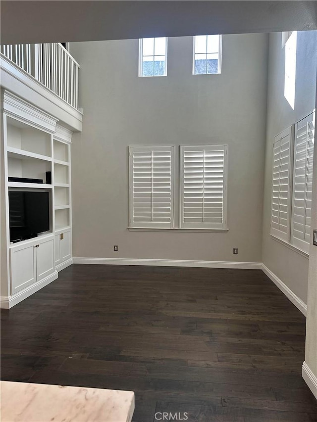 unfurnished living room featuring baseboards and dark wood finished floors