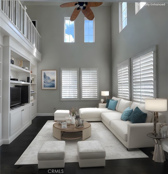 living room featuring dark wood-type flooring, baseboards, ceiling fan, and a high ceiling