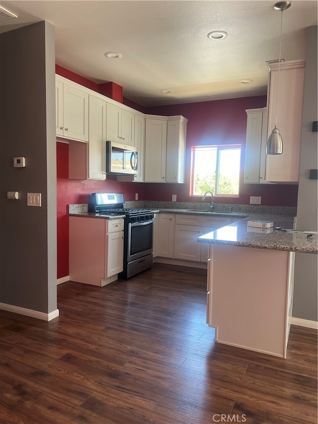 kitchen featuring appliances with stainless steel finishes, dark hardwood / wood-style flooring, white cabinetry, and pendant lighting