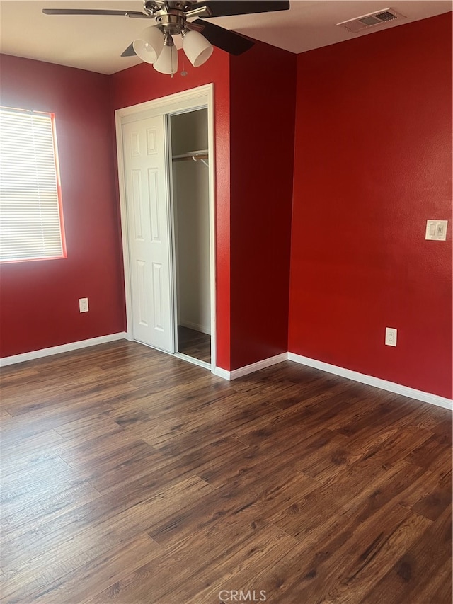 unfurnished bedroom with dark wood-type flooring, a closet, and ceiling fan