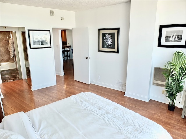 bedroom with light hardwood / wood-style flooring, a textured ceiling, and ensuite bath