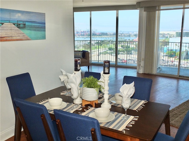 dining space with a water view, hardwood / wood-style flooring, and expansive windows