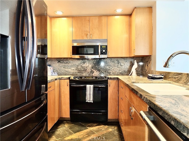 kitchen with light stone countertops, stainless steel appliances, sink, and backsplash